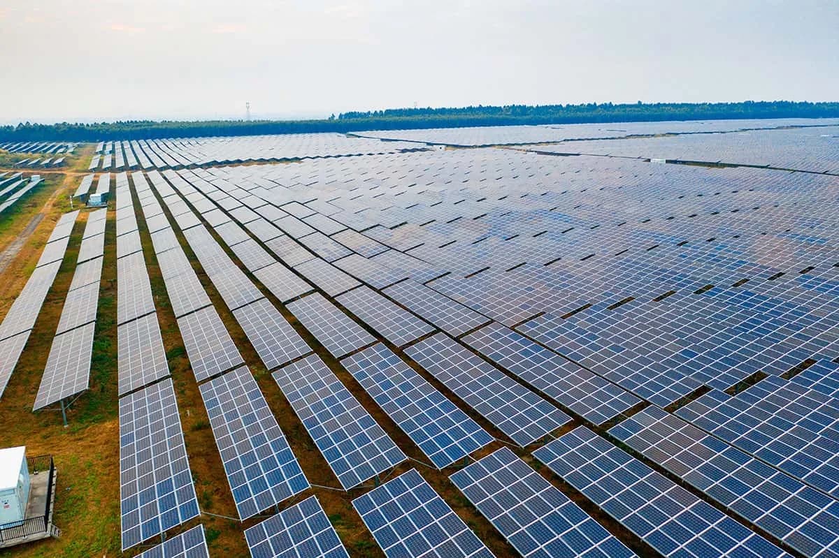 Panou fotovoltaic în prim-plan, cu un câmp verde în fundal